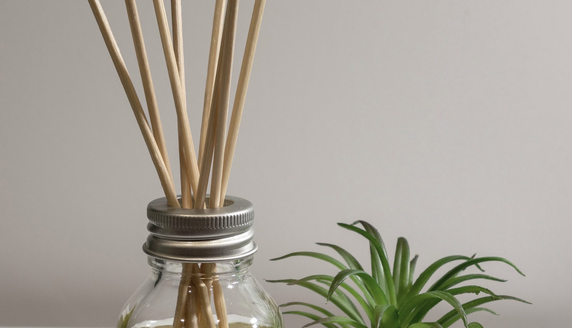 A glass reed diffuser with rattan reeds, close up