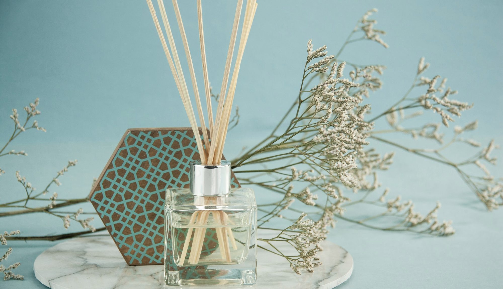 Rattan reeds in a glass diffuser bottle on a pale stone surface
